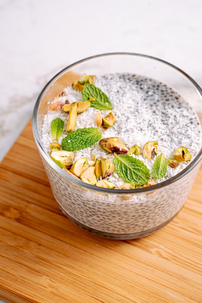 Close-up of a chia pudding topped with coconut flakes, pistachios, and fresh mint leaves.